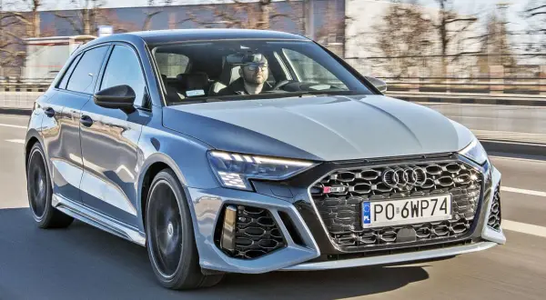 Szary Audi RS3 na drodze. Kierowca w okularach. Sprawdź audi rs3 cena i osiągi.