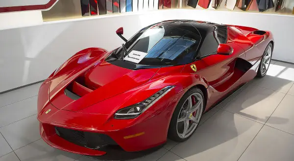 Czerwone Ferrari LaFerrari z czarnym dachem, błyszczące w salonie, gotowe do jazdy.