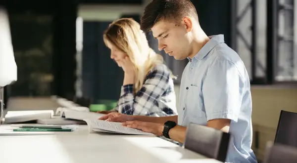 Estudiantes concentrados estudiando para entender como funcionan las oposiciones de maestro.