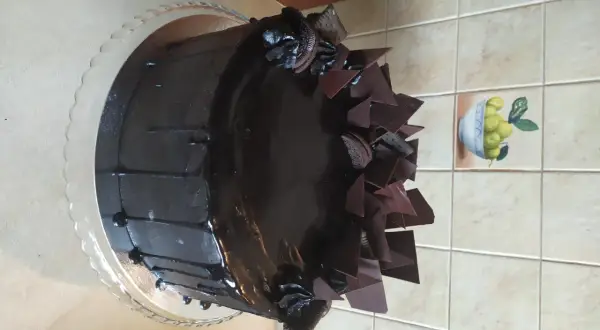 Czekoladowy tort z polewą, czekoladowymi płatkami i ciasteczkami Oreo.