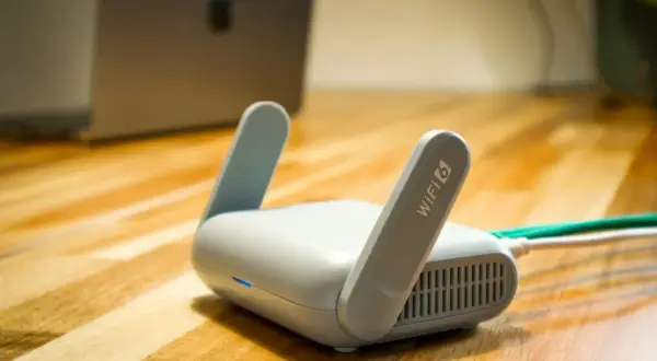 Router Wi-Fi 6 z antenkami, obok laptopa. Czy wiesz, upnp co to jest i jak ułatwia połączenia?