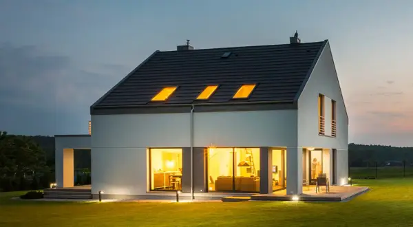 Nowoczesny dom z jasnym, gładkim tynkiem zewnętrznym, który podkreśla jego architekturę. Różne rodzaje tynków zewnętrznych mogą nadać budynkowi unikalny charakter.