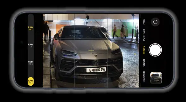 Un'auto sportiva grigia, con targa GMIIBRAW, inquadrata dall'app fotocamera di un iPhone con opzione apple proraw attiva.