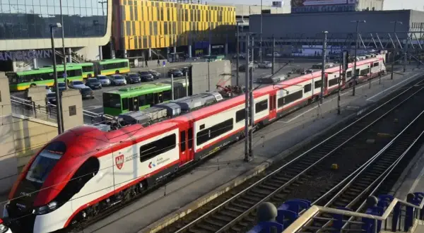 Koleje Wielkopolskie: rozkład jazdy Konin - Poznań. Nowoczesny pociąg na dworcu Poznań Główny, obok zielonych autobusów i samochodów.