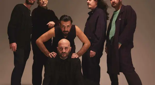 I Negramaro, in posa per "Quel posto che non c'è", sei uomini con sguardi intensi e abiti scuri.