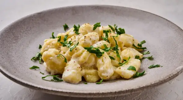 Puszyste gnocchi w kremowym sosie, posypane świeżą natką pietruszki. Idealny sos do gnocchi na szybki obiad.