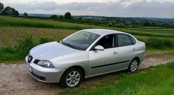 Srebrny Seat Cordoba na tle zielonych pól i pagórków.