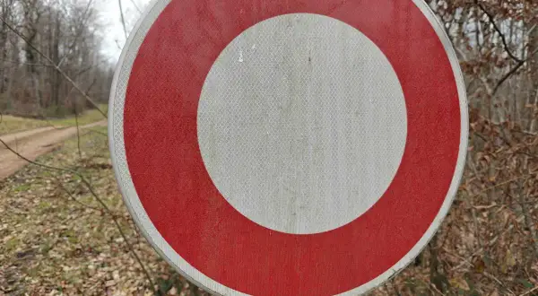 Panneau rond rouge et blanc, interdisant le passage sur un chemin forestier.