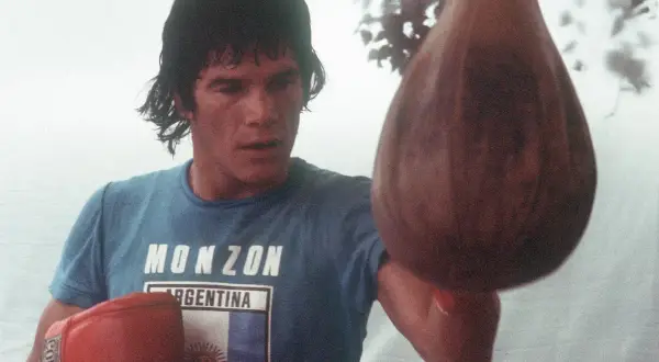 Carlos Monzón, the legendary boxer, trains with a speed bag, his focus intense.