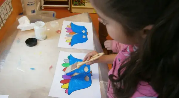 Niña pinta pájaros de colores, preparándose para un día de la paz para niños.