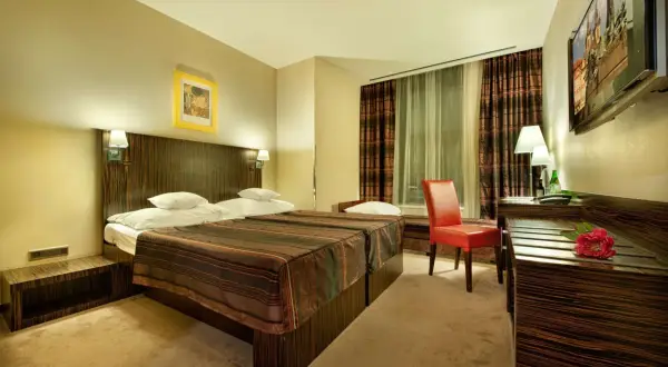 Pokój hotelowy z dwoma łóżkami, czerwonym fotelem i telewizorem.