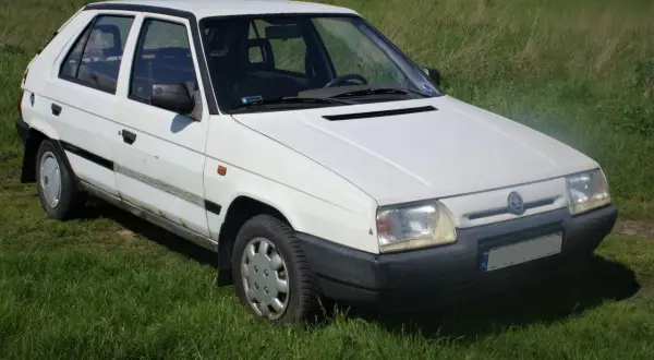 Biały Skoda Favorit stoi na trawie.