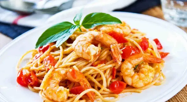 Spaghetti con gamberetti succulenti e pomodorini freschi, guarniti con basilico. Un piatto invitante che profuma di mare.