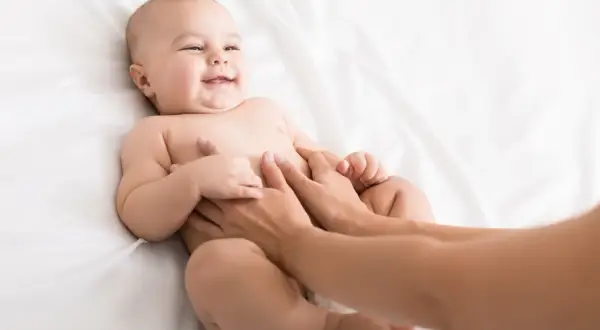 Glad bebis får magmassage på en vit bakgrund.