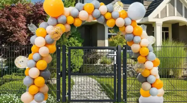 Jak samemu zrobić stojak na balony? Łuk z pomarańczowych, szarych i białych balonów nad bramką.