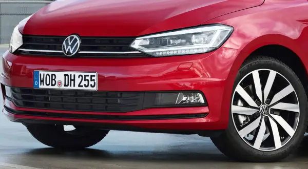 Czerwony Volkswagen Touran z błyszczącym logo i nowoczesnymi światłami.