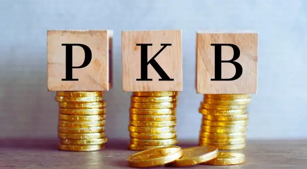 Trzy stosy złotych monet, na których stoją drewniane kostki z literami P, K, B. To symbol tego, co to PKB.