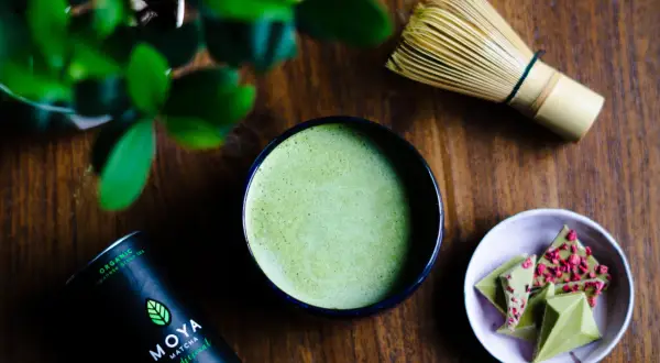 Zielone, spienione matcha w miseczce, obok bambusowa miotełka i czekoladki. To może być najdroższa herbata na świecie, przygotowana z pasją.