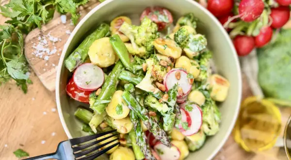 Leckerer Gnocchi Salat mit Spargel, Brokkoli, Radieschen und Pinienkernen, garniert mit frischer Petersilie.