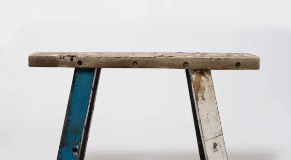 Banc rustique en bois, prêt pour une **rénovation meuble ancien**. Ses pieds bleus et blancs patinés racontent une histoire.