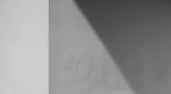 Ściana z widocznym podziałem na jaśniejszą i ciemniejszą część, o chropowatej fakturze. Wygląda jakby użyto klej zamiast tynku zewnętrznego.