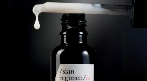 Una goccia di siero cade da un contagocce su una bottiglia scura, un passo essenziale nelle fasi skincare per una pelle radiosa.