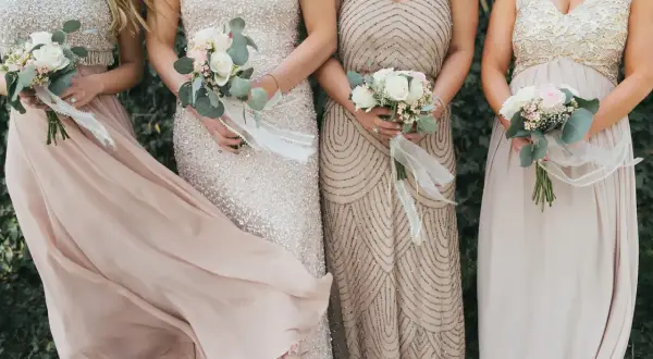Festliche Kleider, die man zur diamantenen Hochzeit anziehen könnte: glitzernde und fließende Stoffe in zarten Farben, gehalten von eleganten Damen mit Blumensträußen.