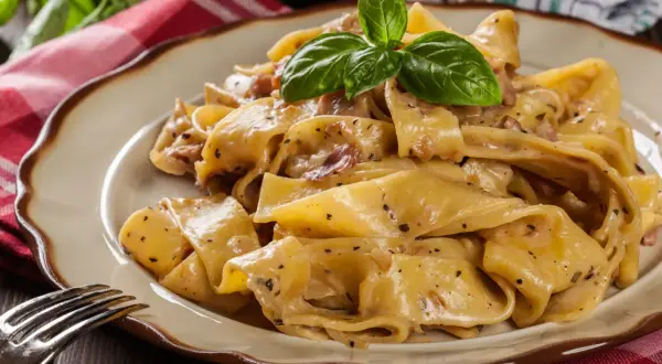 Cremige Pappardelle mit Speck und Kräutern, ein köstliches Pappardelle Rezept, garniert mit frischem Basilikum.
