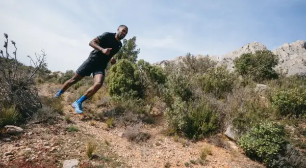 Un coureur en pleine action sur un sentier rocailleux, profitant d'une course à étapes dans un paysage aride et montagneux.
