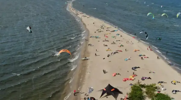 Rewa atrakcje dla dzieci: plaża pełna kolorowych latawców do kitesurfingu i ludzi odpoczywających na piasku.