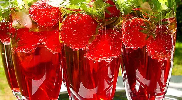 Tre glas med röd midsommar drink fyllda med jordgubbar och mynta. Perfekt för en varm sommardag.