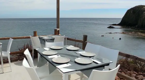Mesas puestas en el restaurante La Isleta, listas para disfrutar de la brisa marina y un buen plato.
