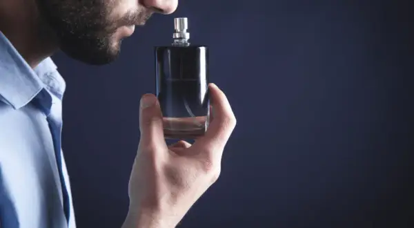 Mężczyzna wącha flakonik, szukając najbardziej trwałych perfum męskich. Elegancki zapach na cały dzień.