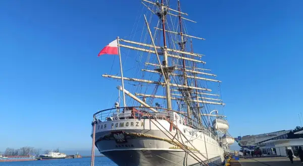 Duma polskiego żeglarstwa, żaglowiec "Dar Pomorza", cumuje przy nabrzeżu. Biało-czerwona flaga dumnie powiewa na maszcie.