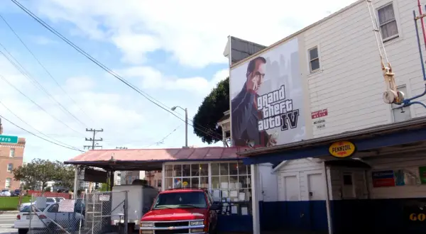 Reklama Grand Theft Auto IV, kiedy wyszło GTA 4, na budynku z czerwonym pickupem na pierwszym planie.