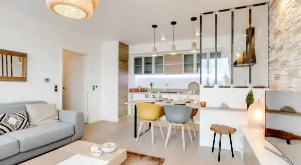 Espace de vie moderne avec cuisine, salle à manger et salon dans la même pièce. Canapé gris, table basse, table de repas et îlot de cuisine.