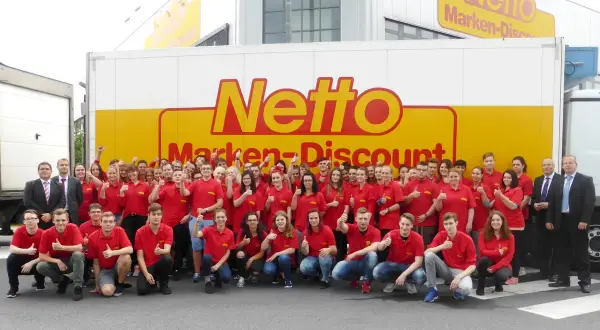 Gruppe von Mitarbeitern in roten T-Shirts vor einem Netto-LKW. Eine gute e-commerce ausbildung gehaltsperspektive für die Zukunft.