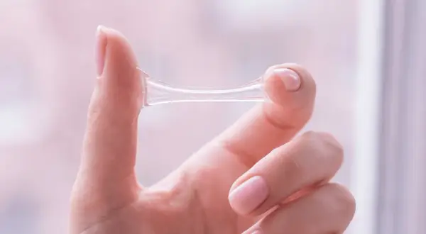 Eine Hand hält eine zähe, klare Substanz, die anzeigt, dass es sich um Ausfluss nach Eisprung handelt.