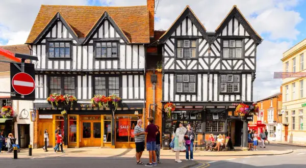 Urokliwe, zabytkowe budynki w Stratford-upon-Avon z charakterystyczną czarno-białą elewacją i kwiecistymi balkonami.