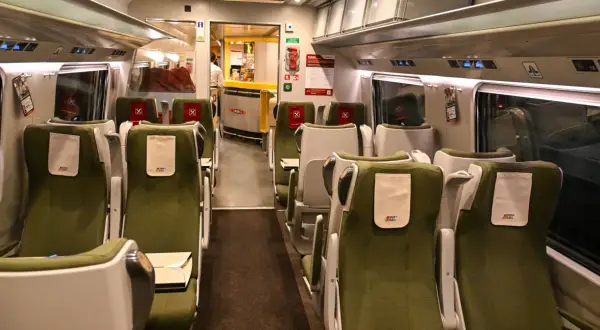 Wnętrze wagonu PKP Intercity z zielonymi siedzeniami i stolikami. Widoczny bar z pracownikiem. Rozkład miejsc IC 38172.