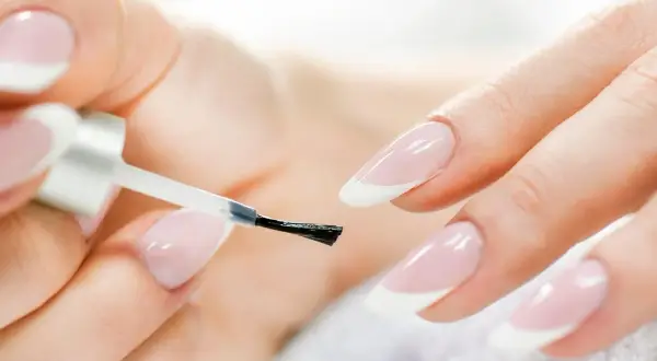 Mani curate che si preparano a fare unghie perfette con smalto trasparente.