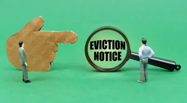 Dito un dito di cartone indica una lente d'ingrandimento con la scritta "EVICTION NOTICE". Un omino guarda la lente, suggerendo un imminente sfratto per finita locazione e canoni non pagati.