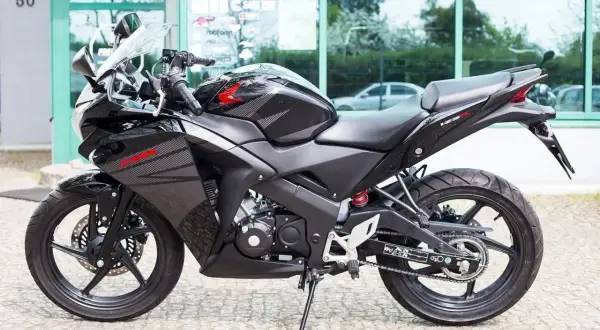 Czarny motocykl Honda CBR 125R z automatyczną skrzynią biegów, gotowy do jazdy po mieście.