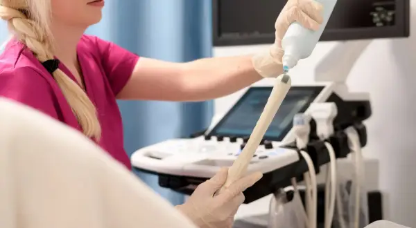 Lekarka przygotowuje sondę USG do badania, aplikując żel. Badanie pozwala ocenić stan endometrium po menopauzie.