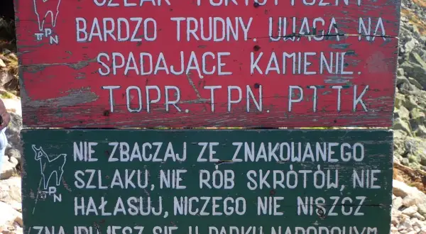 Tabliczka na szlaku turystycznym: "Bardzo trudny, uwaga na spadające kamienie". Niżej: "Nie zbaczaj ze szlaku, nie rób skrótów, nie hałasuj, niczego nie niszcz. Znajdujesz się w Parku Narodowym". Przełęcz Karb.