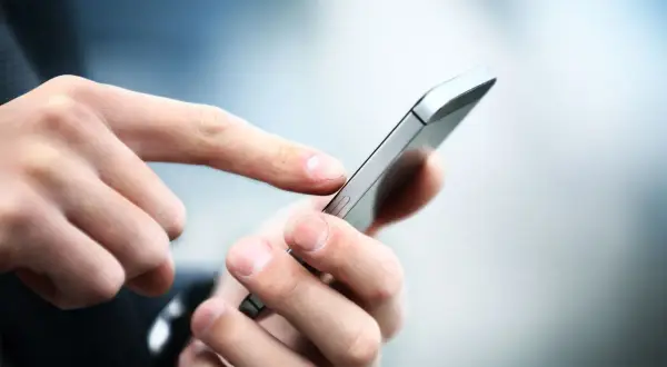 Dłoń z palcem wskazującym dotyka ekranu smartfona, korzystając z aplikacji Citi Handlowy.