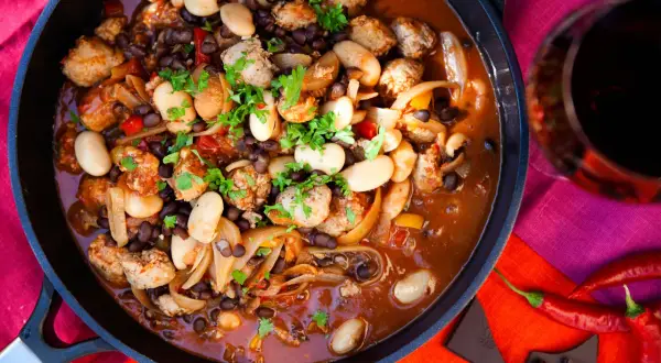 En mustig korvgryta med bönor och lök, perfekt för ett mysigt middagsrecept. Serveras med rödvin och chili.