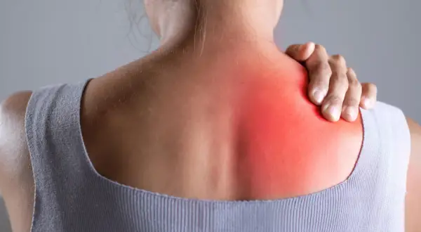 Donna con mano sulla spalla, evidenziata un'area rossa che indica dolore in mezzo alle scapole.