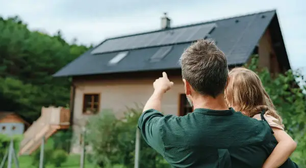 Padre e figlia guardano il tetto con pannelli solari. Un impianto fotovoltaico da 5 kW può produrre molta energia al giorno.