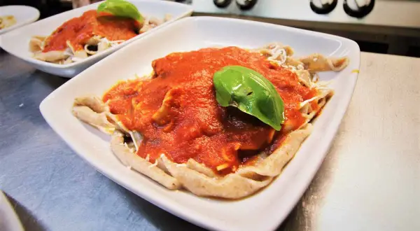 Sagne torte fatte in casa con sugo di pomodoro fresco e basilico, servite in un piatto bianco.